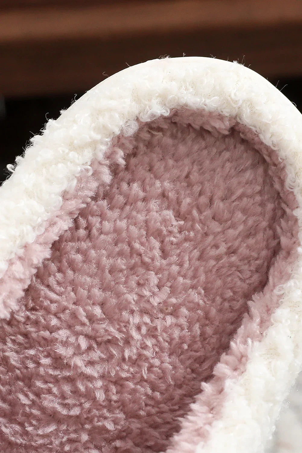 Close-up of a cozy slipper with soft pink fleece interior and white fluffy trim