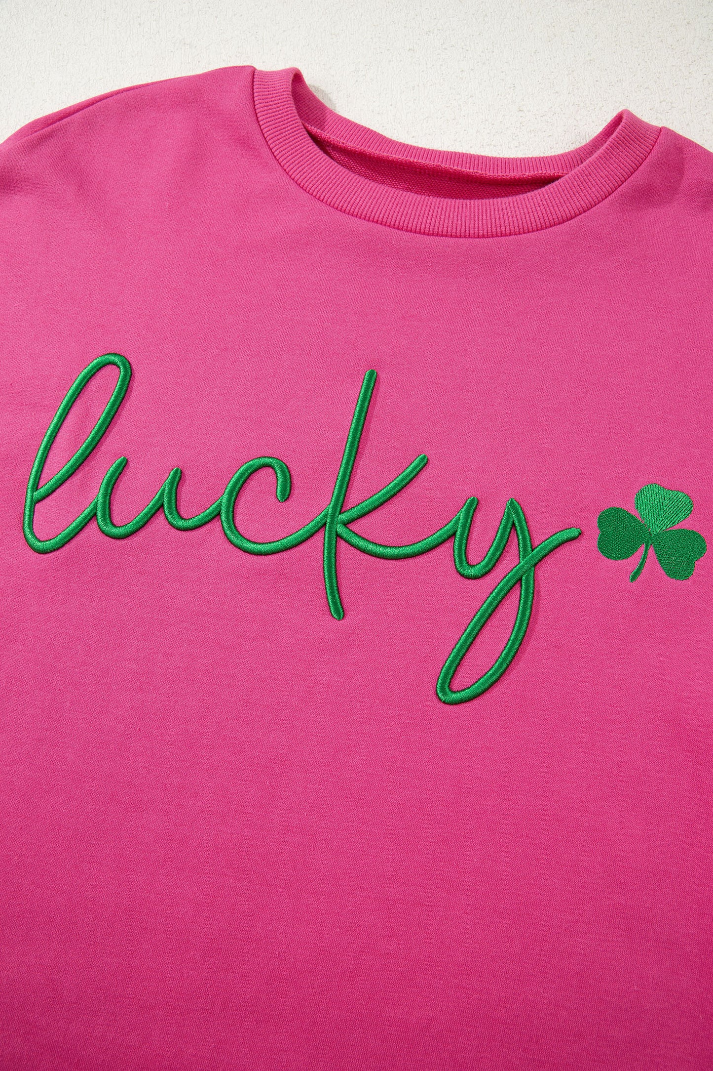 Pink shirt with green 'lucky' text and shamrock on a white background