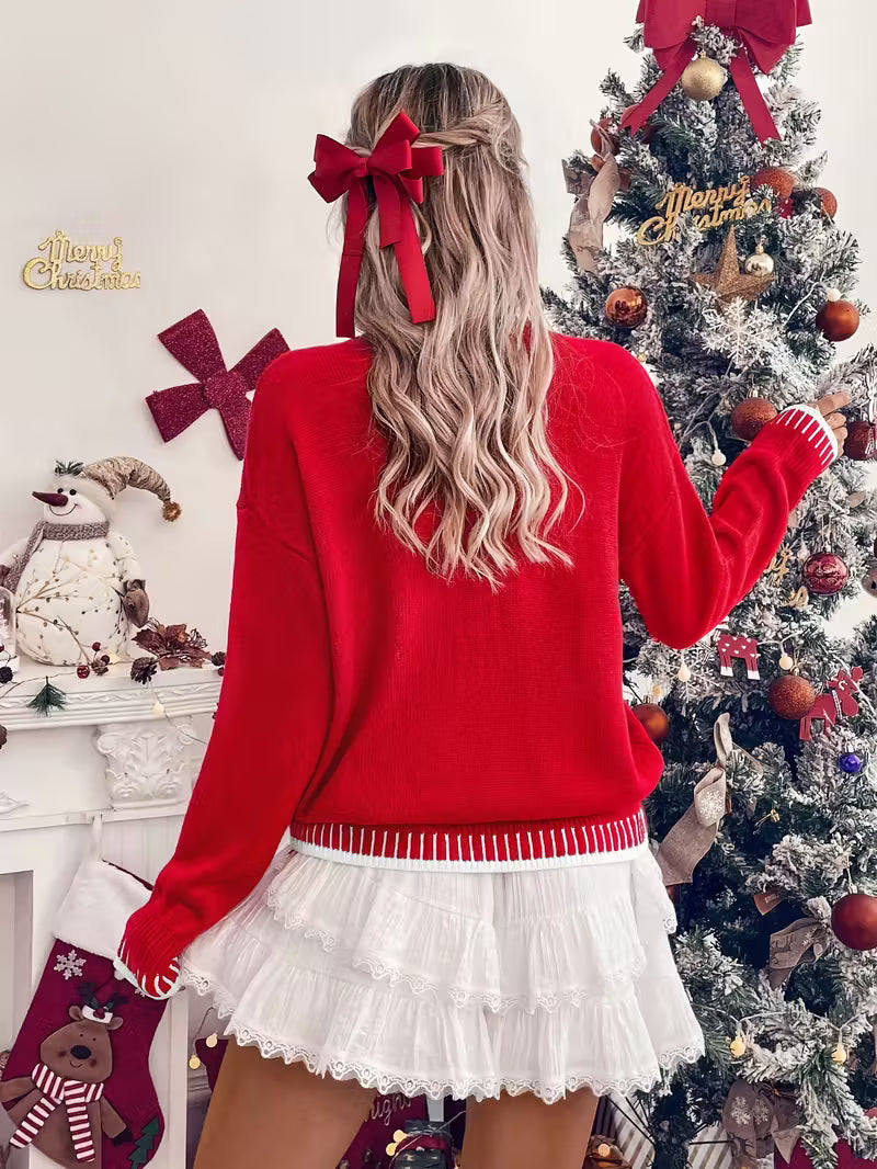 Person wearing a red sweater and white skirt standing in front of a decorated Christmas tree.