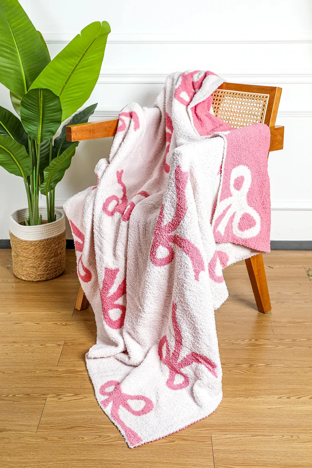 Pink and white patterned cozy blanket draped over a wooden chair with cane backrest indoors