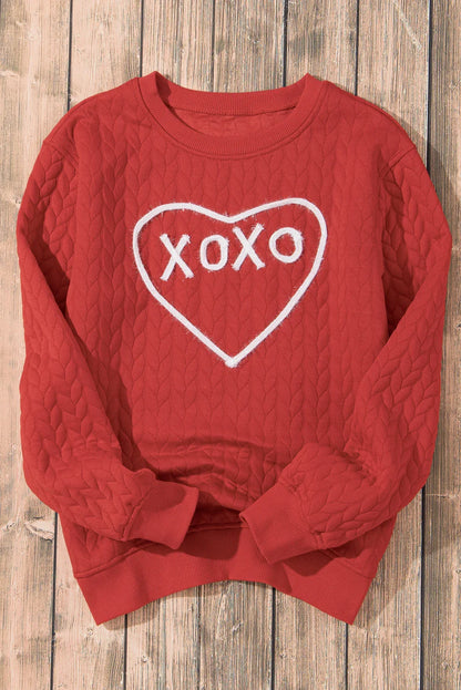 Red quilted sweatshirt with white heart and XOXO design on wooden floor background