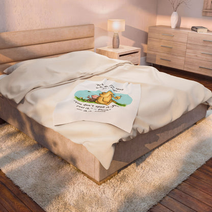 baby crib blankt 40" x 60" with a logo on a  queen bed in a bedroom setting. Blanket takes up a quarter of the bed.