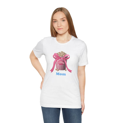 Woman wearing white t-shirt with pink popcorn bucket graphic and blue text saying Mom