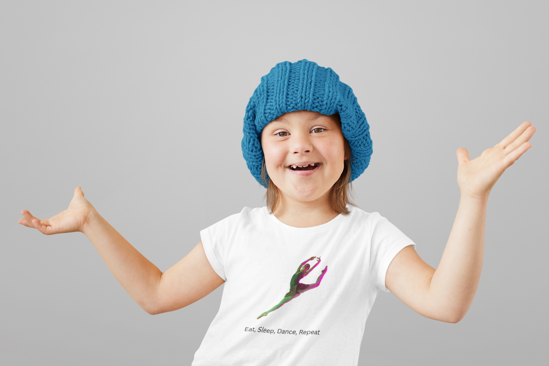 Child wearing a blue knitted hat and white t-shirt with a colorful design on a gray background