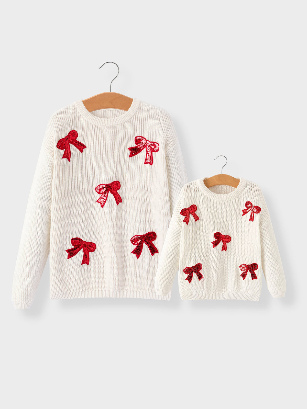 Mommy and Me Sweaters | Red Sequin Bows: Adult and child sweaters on hangers