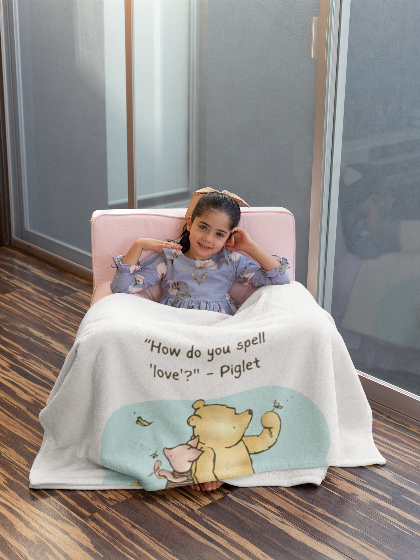Child sitting on a pink chair with a Winnie the Pooh-themed blanket