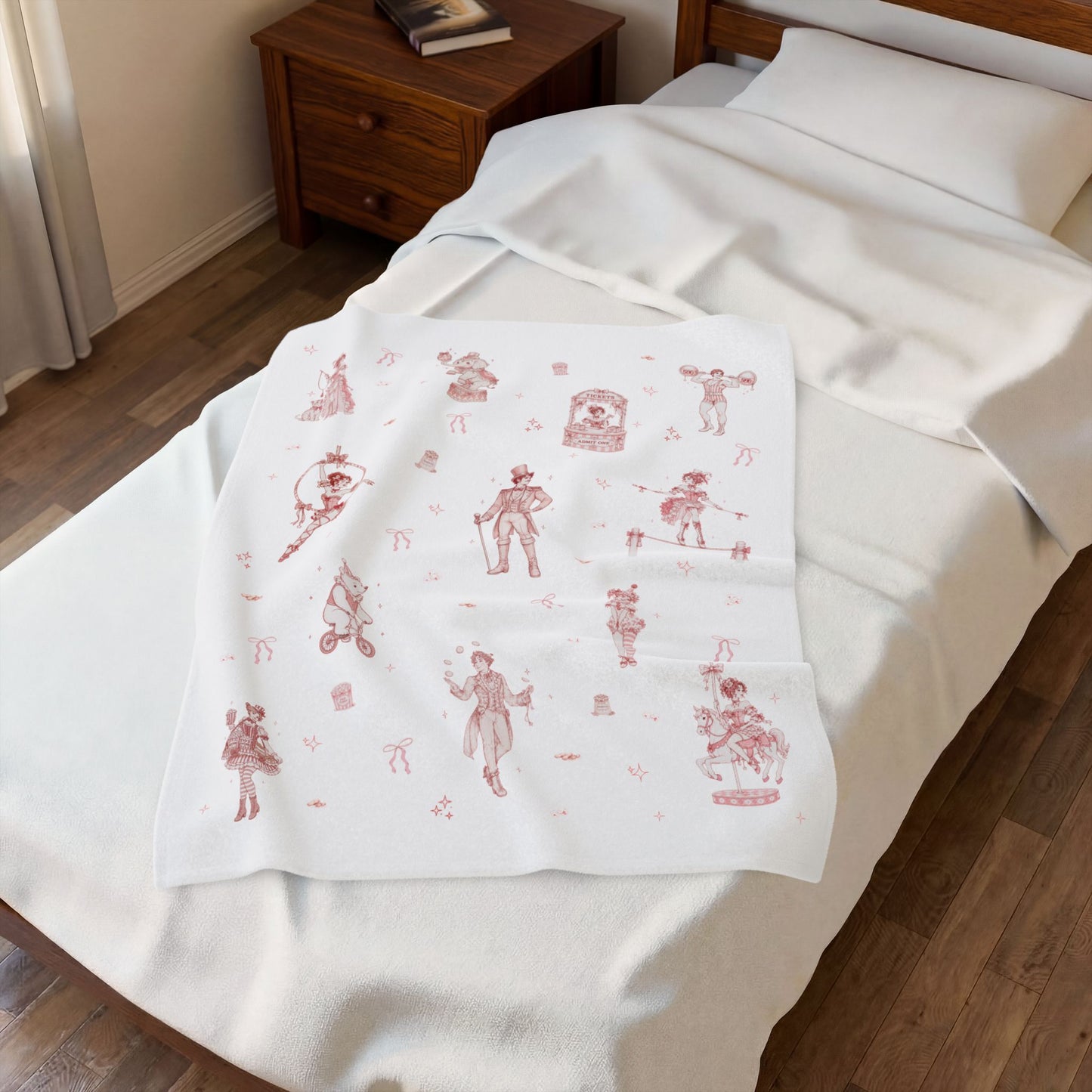 Baby blanket with red and pink coquette circus print on a bed