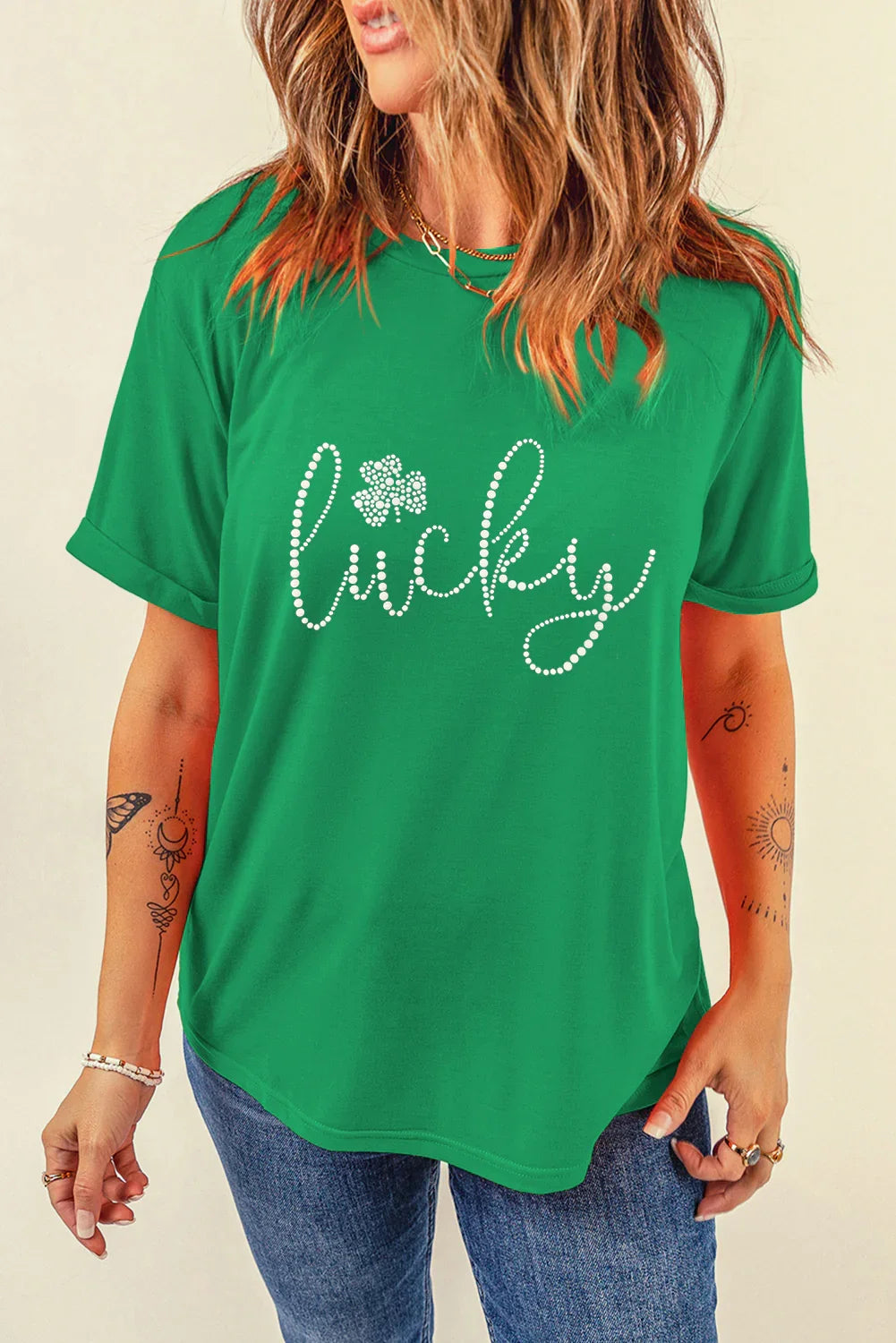 Woman wearing green t-shirt with rhinestone design spelling lucky and shamrock detail