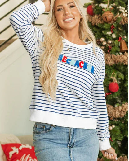 Smiling woman in striped sweater and denim skirt posing near decorated Christmas tree with gifts