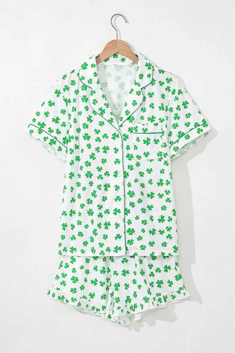 Green shamrock pattern pajama set on a hanger against a white background