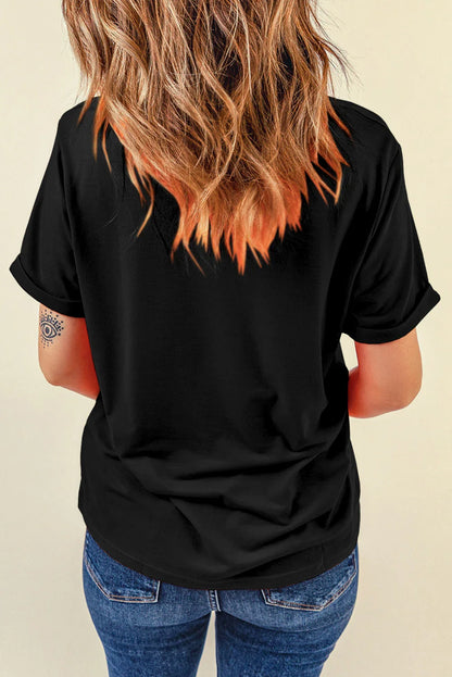 Back view of woman with wavy brown and orange hair wearing a black rolled-sleeve t-shirt and blue jeans
