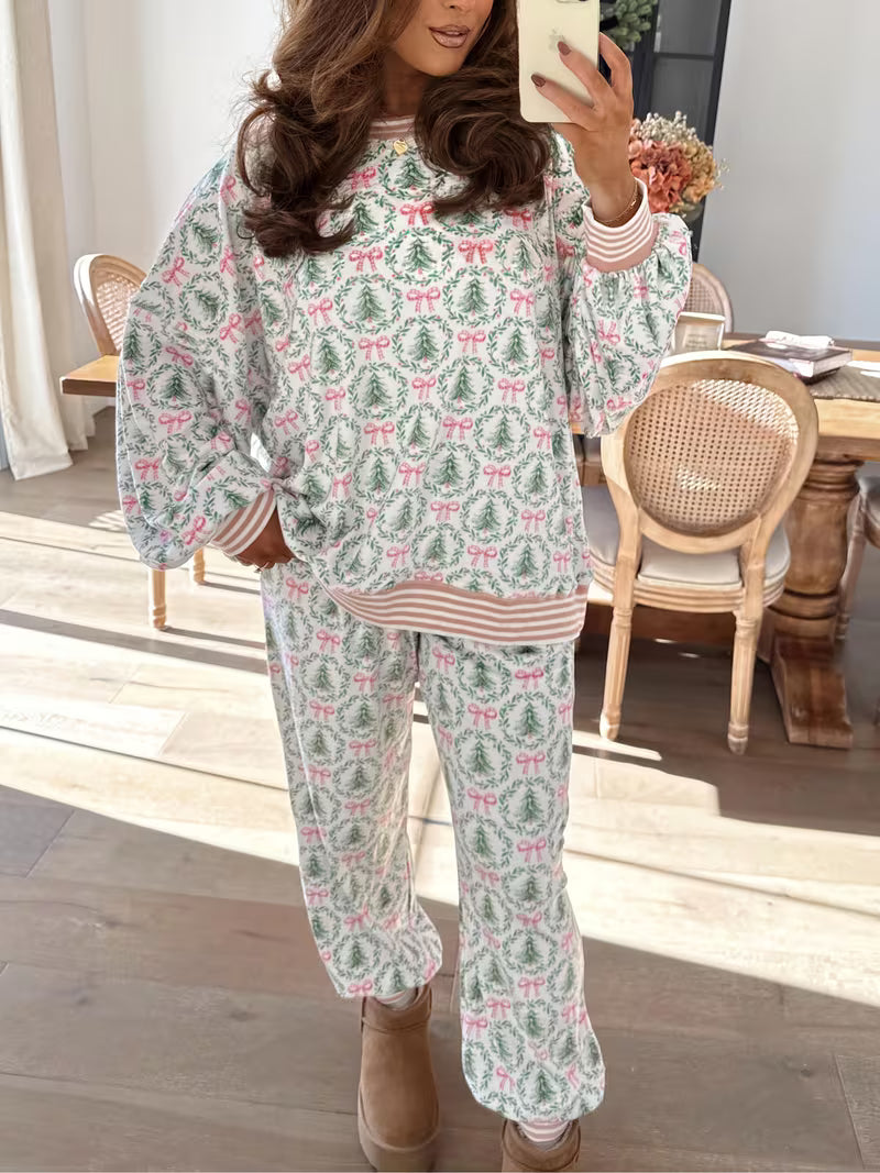 Woman taking a mirror selfie wearing a festive pajama set with Christmas trees and bows in a home setting.