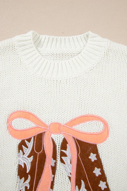 White knit sweater with a detailed applique of brown cowboy boots tied with a pink ribbon