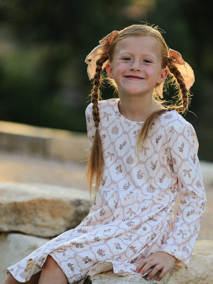 Girls Fall Dress | Pumpkin Bow Twirl: Model seated in printed dress