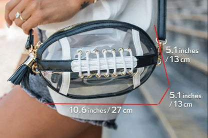 Woman wearing white t-shirt and denim shorts holding a transparent black and white crossbody bag with tassel