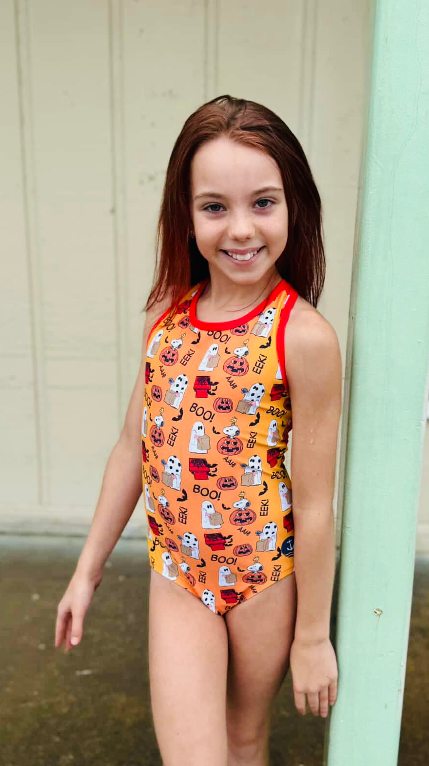 Model wearing the orange Great Pumpkin Snoopy leotard with red scoop-neck trim outdoors