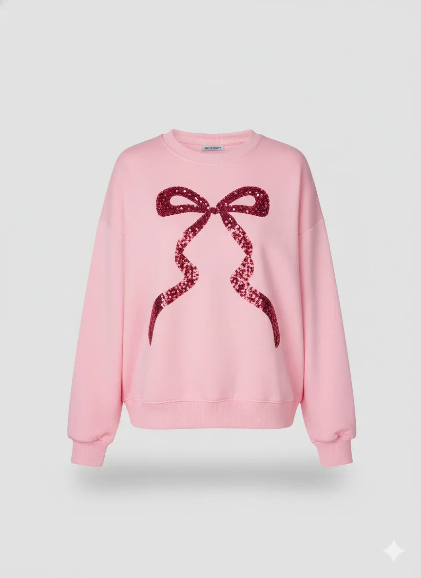 Pink sweatshirt with a red sequin bow design on a light gray background