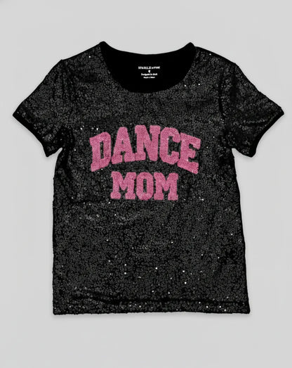 Black glittery t-shirt with 'DANCE MOM' text in pink on a light gray background