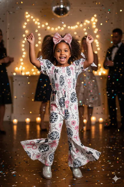 Child in a patterned outfit with raised arms in a festive setting with lights and confetti.