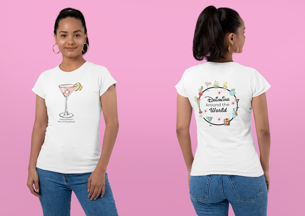A woman modeling a white graphic T-shirt shown from both front and back against a solid pink background. The front features a Sleeping Beauty inspired cocktail with the text "Sleeping Beauty? Nah, Drinking Beauty! and the back says  'Drinking Around the World"