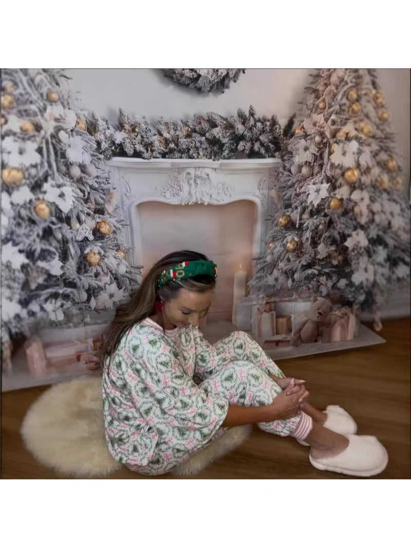 Woman sitting on a rug in front of a decorated fireplace with Christmas trees.