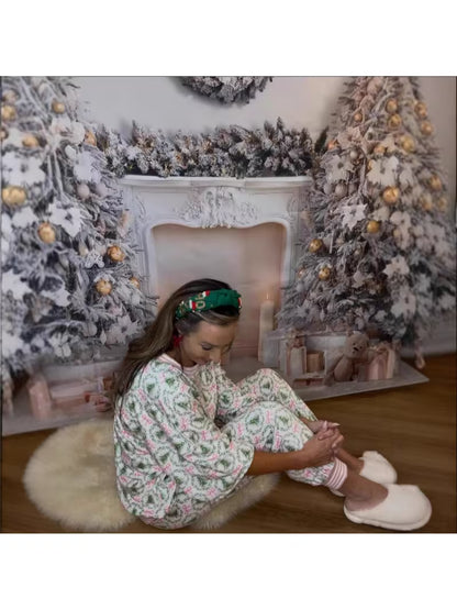 Woman sitting on a rug in front of a decorated fireplace with Christmas trees.