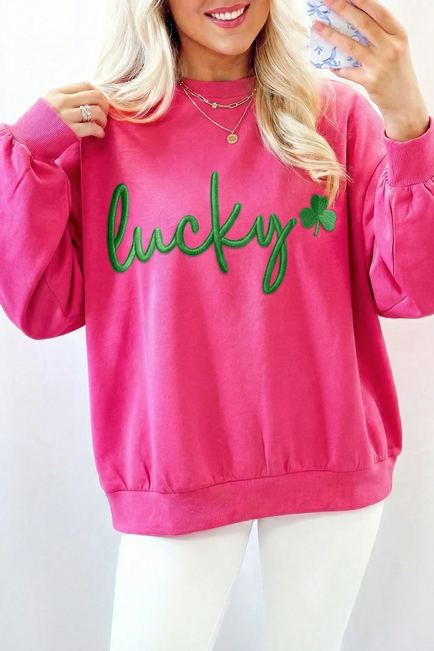 Person wearing a pink sweatshirt with 'lucky' and a shamrock on a white background