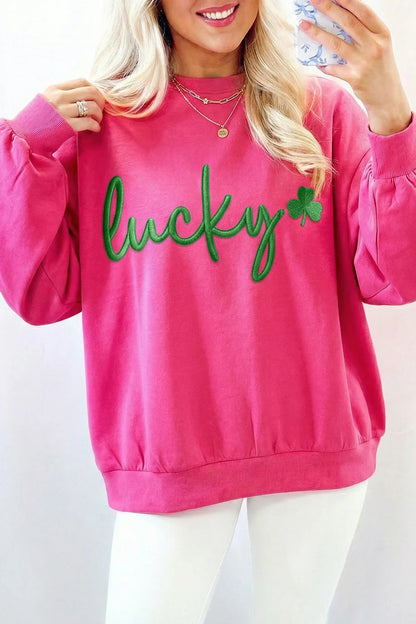 Person wearing a pink sweatshirt with 'lucky' and a shamrock on a white background