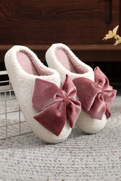 Cozy white fleece slippers with large soft pink velvet bows on woven rug