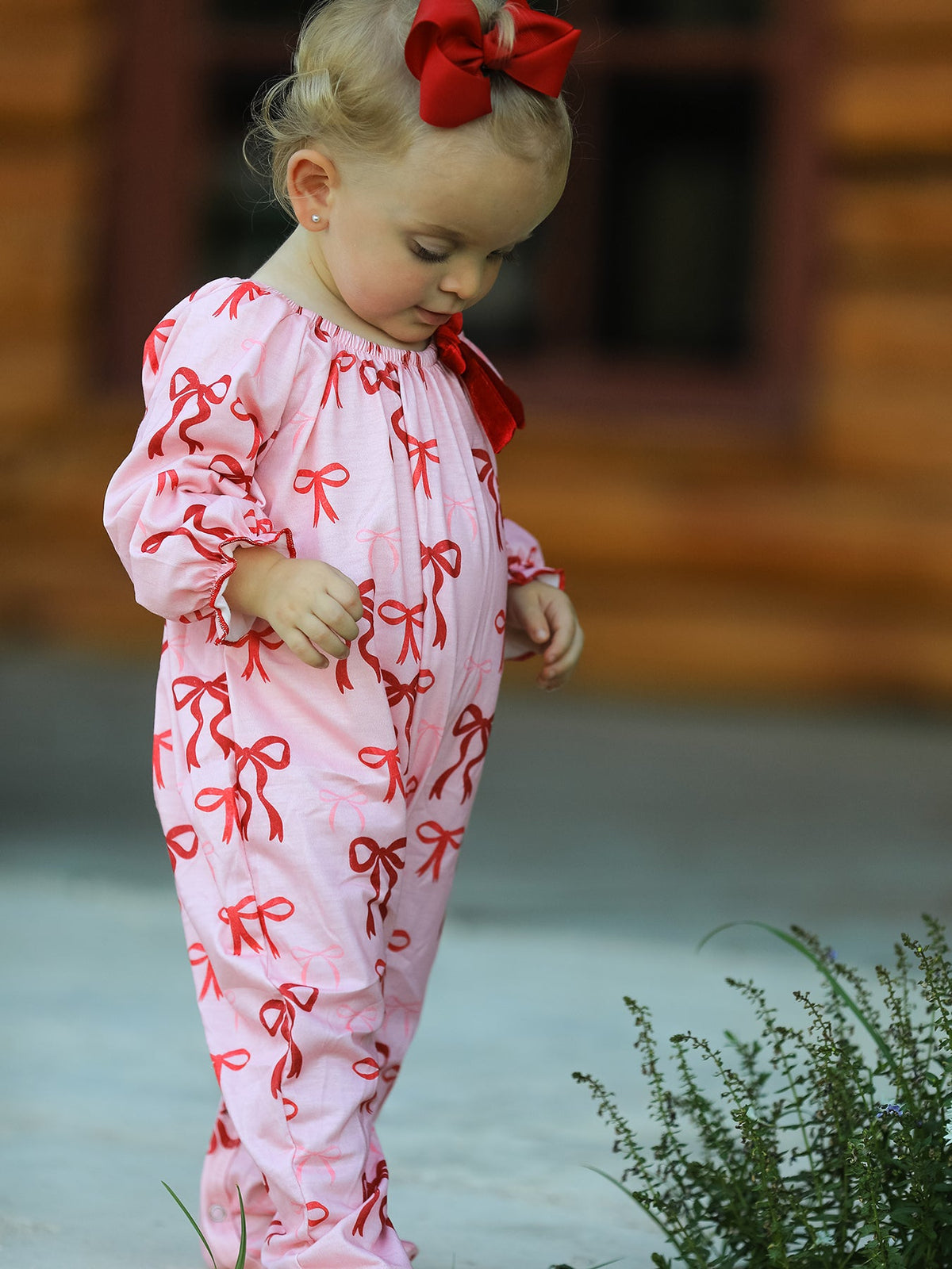 Baby Girl Romper | Pink Christmas Bow Print: Baby looking down at front fit